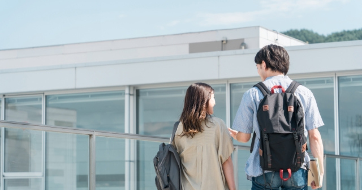 学校の敷地内を歩く男性と女性の学生