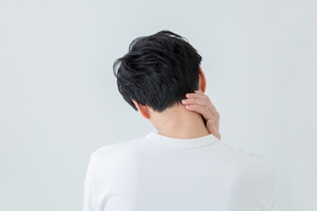首筋を押さえる後ろ姿の男性