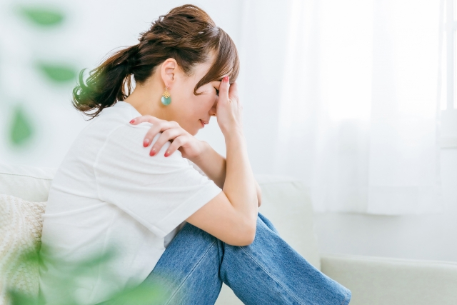 額に手を当てて体調が悪そうな女性