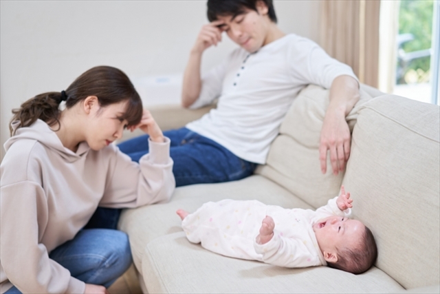 赤ちゃんを目の前に悩んでいる姿の夫婦