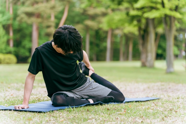 芝生の上でストレッチをする男性