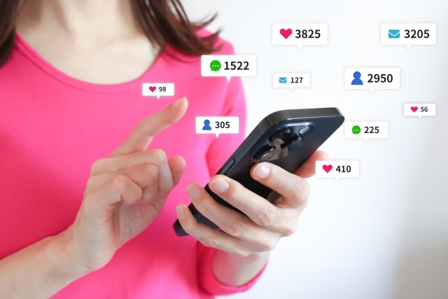 スマホを片手にSNSを閲覧する女性