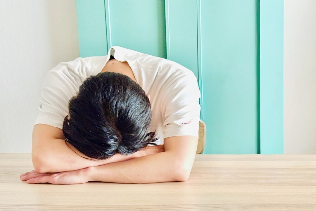 机に突っ伏して落ち込んでいる男性