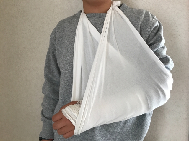 三角巾で腕を吊っている男性