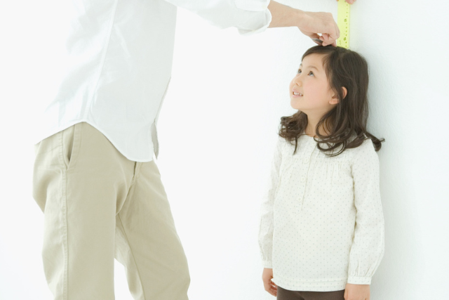 親に身長を測ってもらっている女の子
